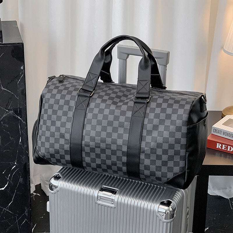 Feldacks weekend bag with shoe compartment in black checkered pattern sitting on silver suitcase