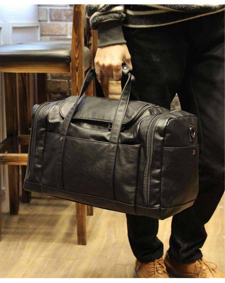 Feldacks black urban style PU leather weekend bag held by person in casual outfit