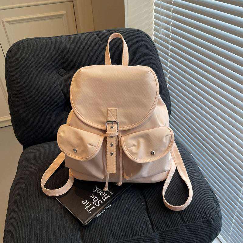 Feldacks beige casual all-match backpack for women with front pockets and buckle closure on black chair