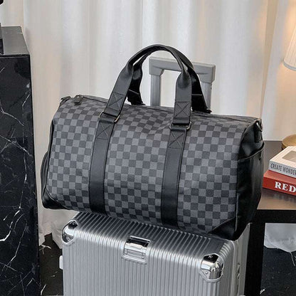 Feldacks weekend bag with shoe compartment in black checkered pattern sitting on silver suitcase