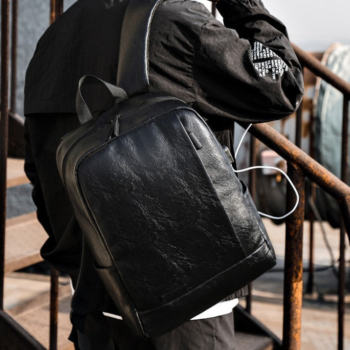 UrbanFlex men's laptop backpack by Feldacks in black worn by a man outdoors with earphones